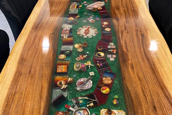 An epoxy river table with a Mexico theme. The river vein was made using UltraClear Deep Pour Epoxy and has been pigmented a deep green color, with many themed embedments, and an UltraClear Bar & Table Top Epoxy topcoating covers the entire table top.
