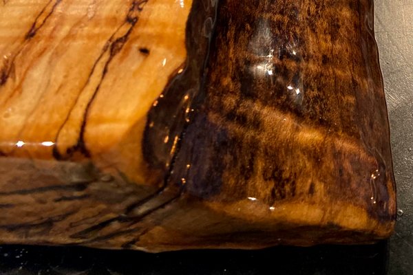 A close-up view of one corner of a live-edge wooden epoxy table top that has been coated with UltraClear Bar & Table Top Epoxy.