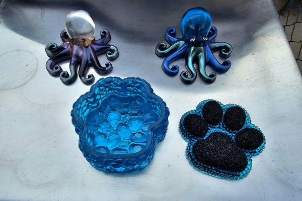 Several piece of epoxy resin art—two shaped like octopi, and one shaped like a paw print.