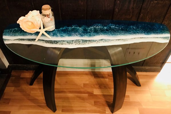 A glass console table near the entrance to someone's home. UltraClear Art & Craft Epoxy has been used to create ocean-wave art on top of the glass.