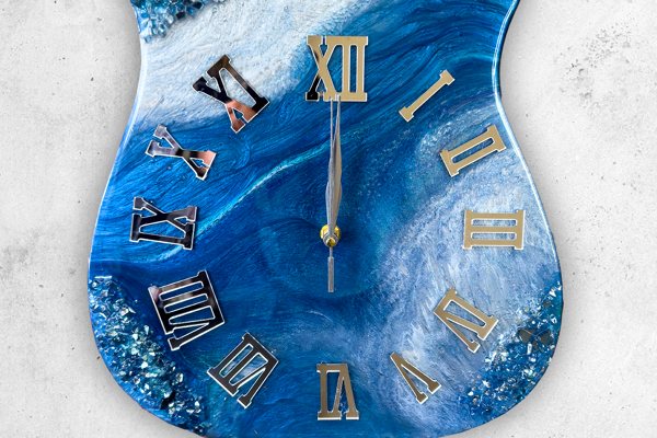 An epoxy wall clock shaped like a guitar head. It consists of multiple differently colored batches of epoxy poured into a mold.