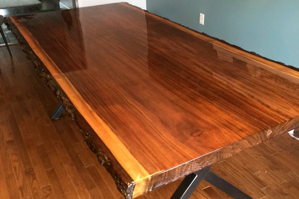 A live-edge wooden dining table with an UltraClear Bar & Table Top Epoxy finish.