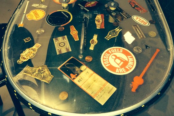 A transparent epoxy work table with a variety of personal mementos, stickers, and decals embedded by the owner. It was finished with UltraClear Bar & Table Top Epoxy.