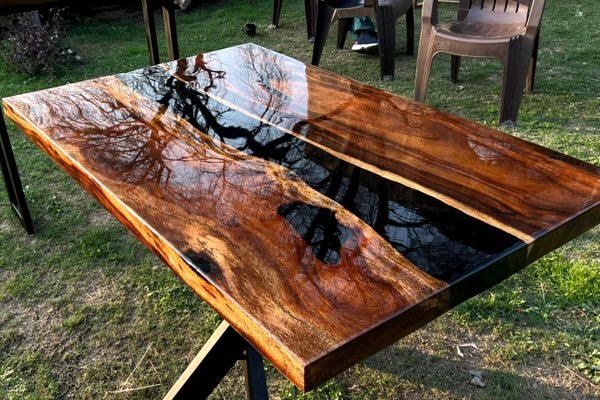An epoxy river table outside, where the reflection of the sky can be see in its perfectly smooth glass-like topcoat of UltraClear Bar & Table Top Epoxy.