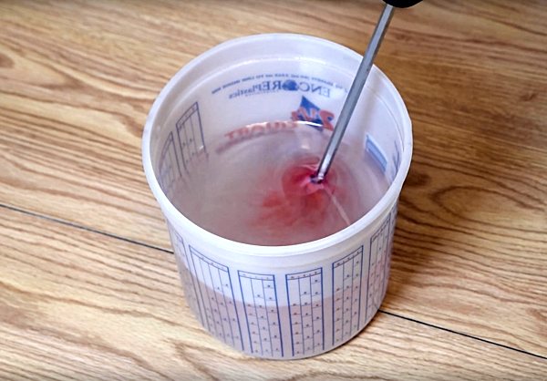 A batch of UltraClear epoxy resin being mixed with a mixing drill bit attached to a power drill.
