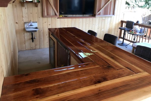 A wooden epoxy bar top in an outdoor setting. It's been sealed with UltraClear Bar & Table Top Epoxy for a long-lasting finish that can withstand heavy use and inclement weather.