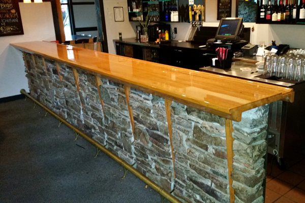 A wooden epoxy commercial bar top with a crystal-clear coating of UltraClear Bar & Table Top Epoxy. This epoxy is highly protective and perfect for high-traffic environments like the one shown.