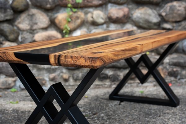 A wooden epoxy coffee table with an opaque black-tinted river vein and black metal table legs.