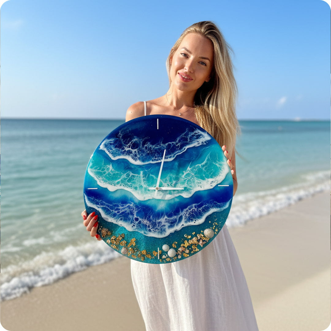 Ilona holding a decorative clock with ocean design on a beach