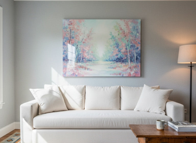 A pastel forest landscape painting with an epoxy resin coating hangs above a white sofa in a softly lit living room, its glossy surface reflecting natural sunlight.
