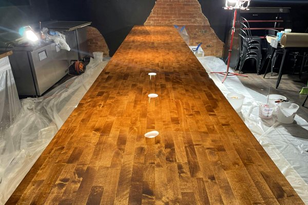 An extra-long wooden commercial bar top with a pristine UltraClear Bar & Table Top Epoxy finish.