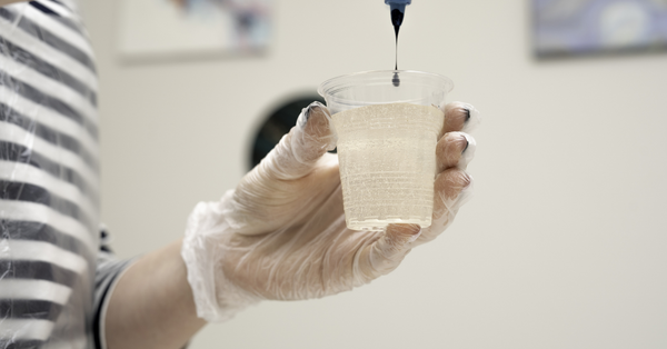 Black liquid pigment being added to a cup of mixed epoxy resin