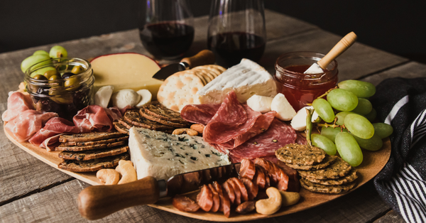 A large charcuterie board covered in meats, cheese, and fruit