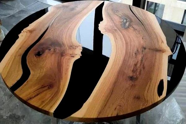 A large round epoxy river table, featuring several opaque black-tinted river veins made using UltraClear Deep Pour Epoxy.
