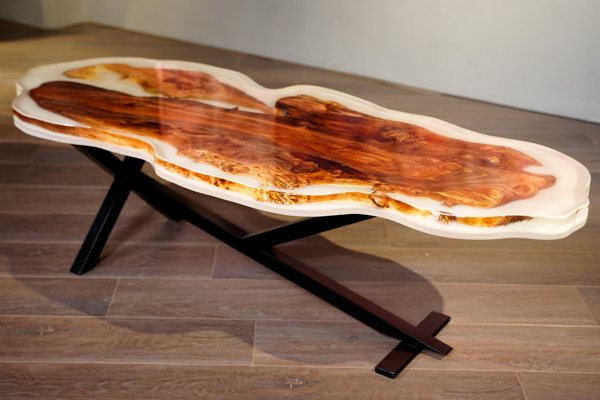 An UltraCler Deep Pour Epoxy coffee table with an unsusual shape. It consists of an irregular slab of wood immersed in two layers of epoxy. The first layer is thick and pigmented white; the second is clear and topcoats the entire project.