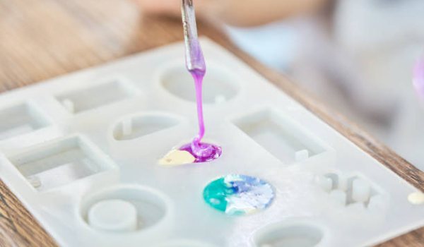 A mold for making resin art and jewelry. Two of the section have colored epoxy resin in them, waiting to cure.