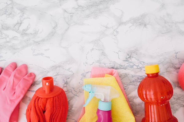 A variety of cleaning supplies resting on an epoxy countertop.