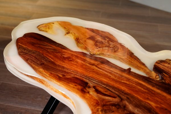 An epoxy coffee table consisting of a wooden slab nearly enveloped by a thick layer of white-pigmented UltraClear Deep Pour Epoxy. The top of the wood is still mostly visible, as if it was floating in the epoxy finsh.