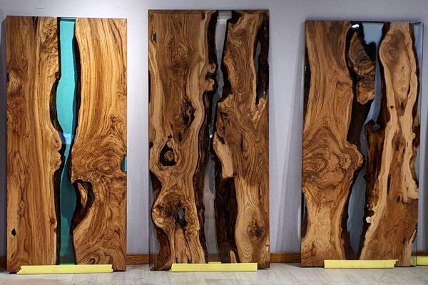 Three separate epoxy art projects featuring slabs of wood with river veins in between. Each vein is a different color and what constructed carefully and safely.
