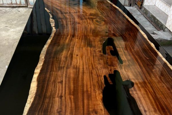 An epoxy river table with multiple river veins of UltraClear Deep Pour Epoxy on either side lengthwise. The veins are opaque with a black tint.