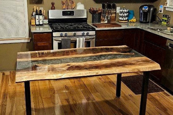 An epoxy river table made using UltraClear Deep Pour Epoxy and a dark gray powder pigment. The table has been topcoated with a clear layer of UltraClear Bar & Table Top Epoxy.