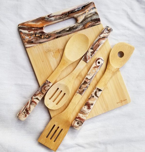 Wooden cooking utensils and a wooden cutting board, each with colorful epoxy resin ornamentation.