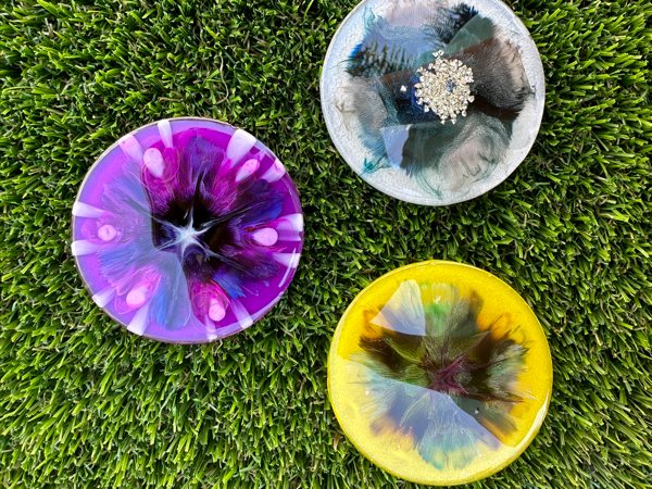 Three different epoxy coasters made with epoxy, liquid dyes, and alcohol inks.