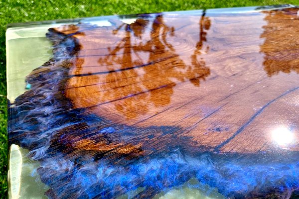 An extra-thick epoxy table top made with a raw wooden slab and a pigmented seal coat of epoxy. The entire piece is encased in a thick translucent coating of deep pour epoxy.