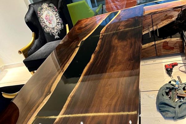 An epoxy river table with an opaque black river vein made of UltraClear Deep Pour Epoxy and resin dye. The table has been topcoated with UltraClear Bar & Table Top Epoxy.