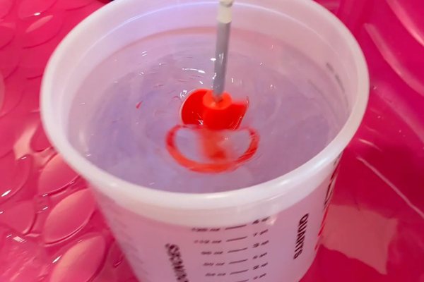 A large batch of UltraClear Art & Craft Epoxy being mixed by power drill with a mixing bit attached.