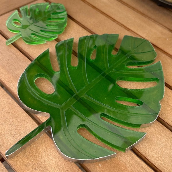 Two green epoxy resin coasters shaped like leaves and colored with Pigmently Epoxy Dyes.