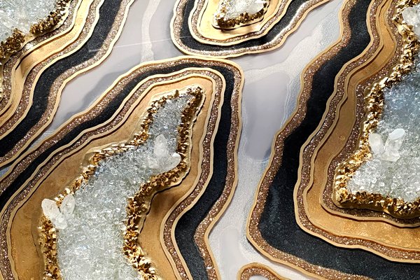 A work of textured epoxy art, featuring gold and white veins of UltraClear Art & Craft Epoxy, along with strips of metal, geode-like crystals, and glitter.