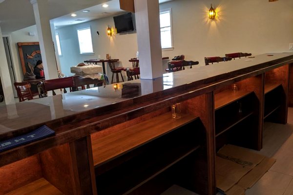 A beautiful wooden commercial bar top with an UltraClear Bar & Table Top Epoxy finish, positioned inside a restaurant.