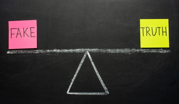 A blackboard with two notes attached labeled "FAKE" and "TRUTH"