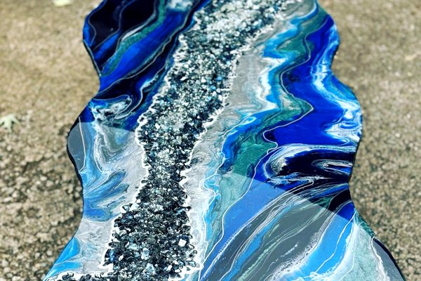 A decorative epoxy table top consisting of several streaked UltraClear Art & Craft Epoxy layers of blue and white tones. The edges are wavy and there is a strip of crushed glass that crosses diagonally from one corner to the opposite.