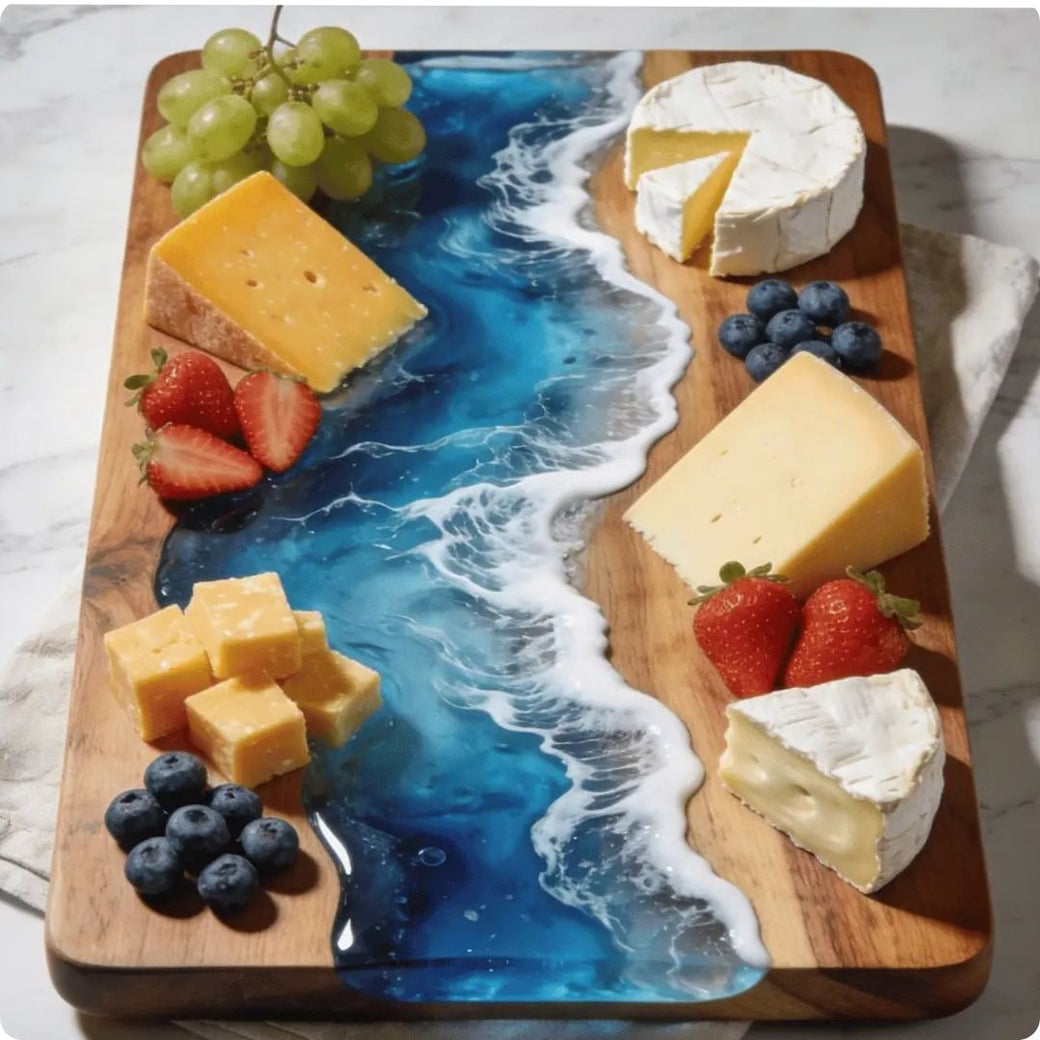 Wooden charcuterie board with cheese, fruits, and a decorative ocean design.