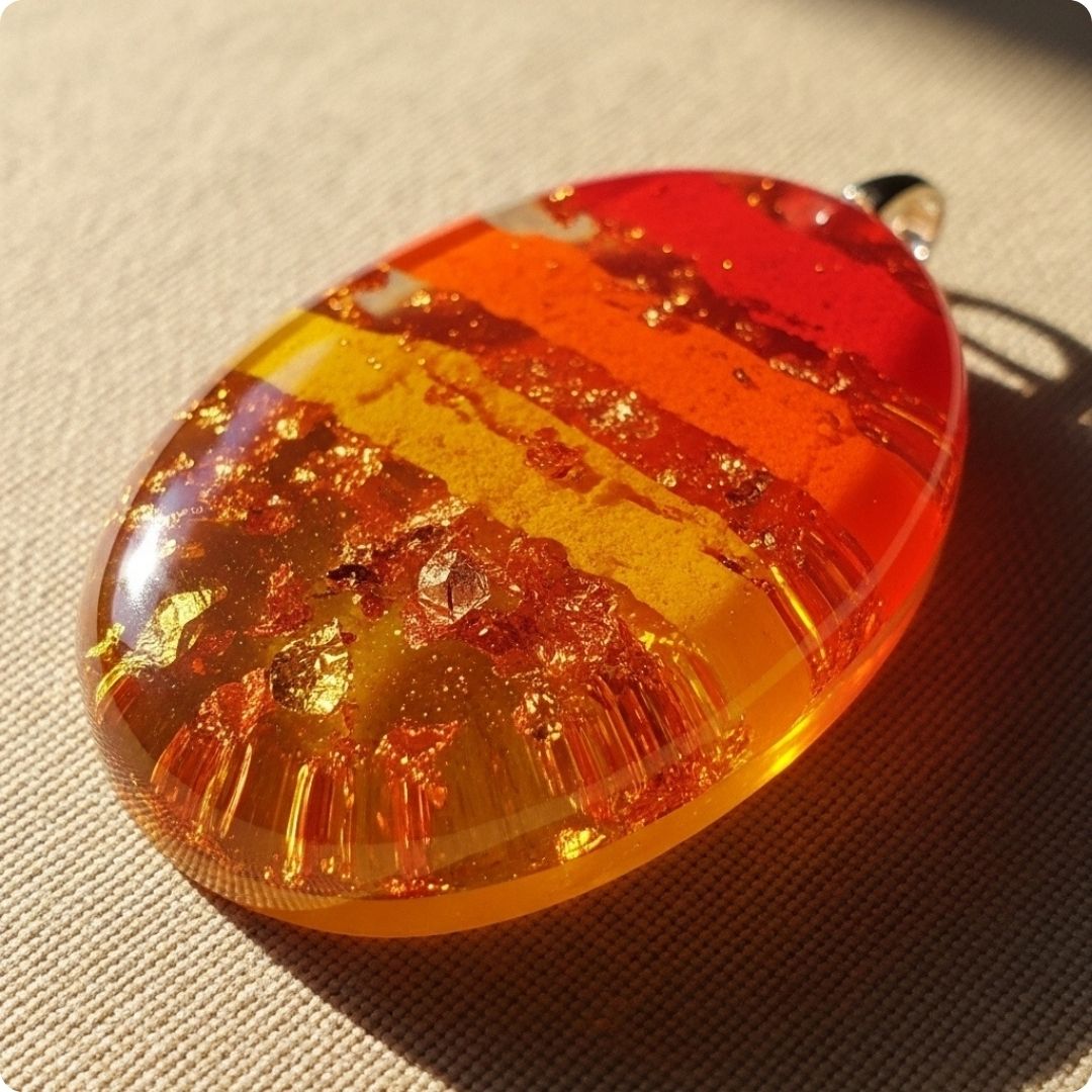 Amber-colored pendant with embedded gold on a textured surface