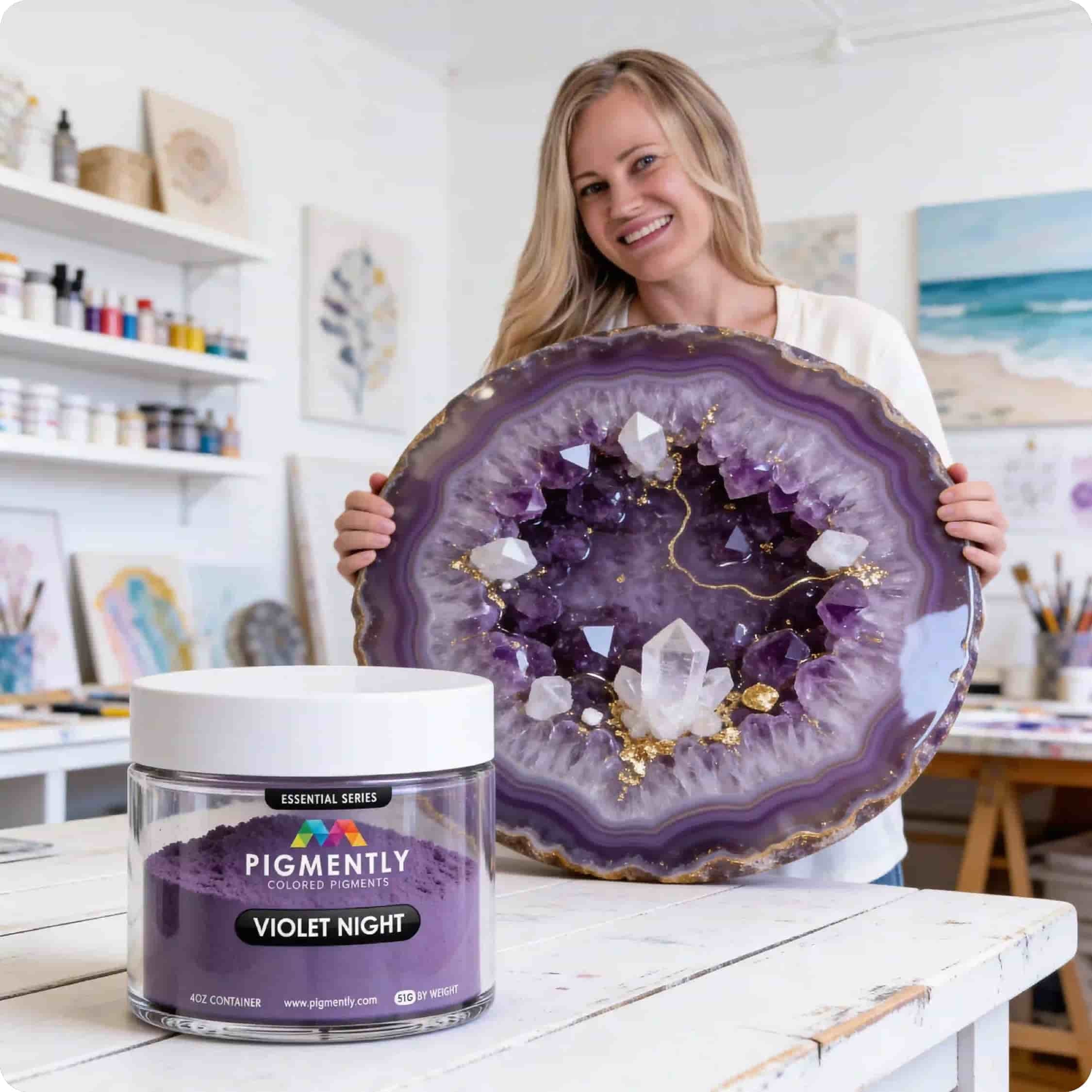 Meike holding a large purple crystal geode with a container of Pigmently Violet Night paint in an art studio.