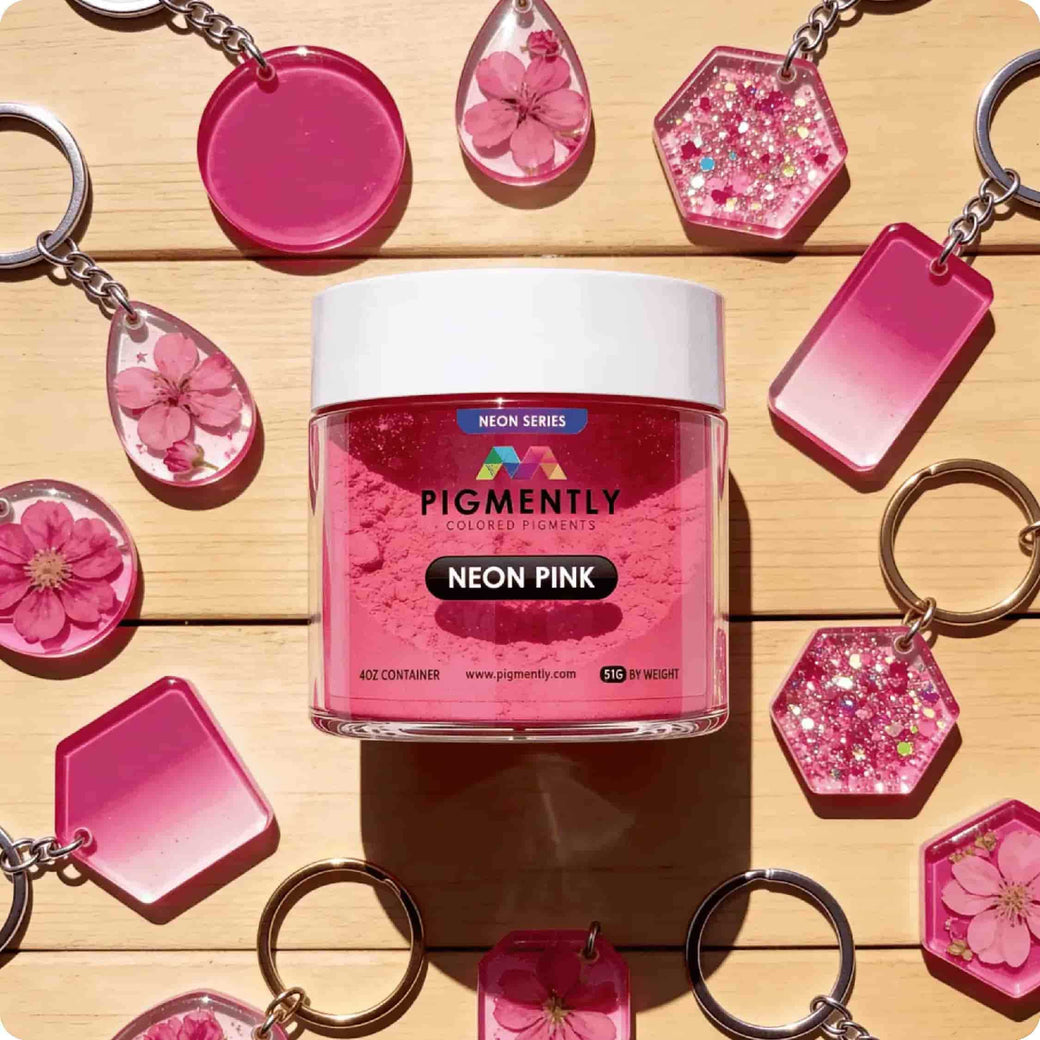 Neon Pink pigment container with pink keychains and decorative items on a wooden surface